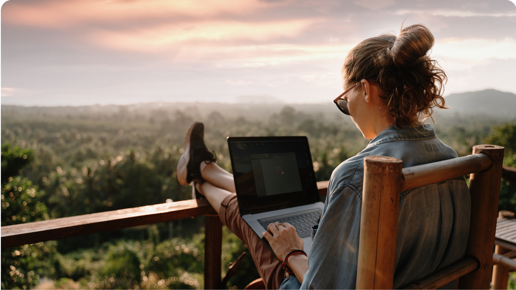 Woman sitting on a chair in the balcony working on a laptop