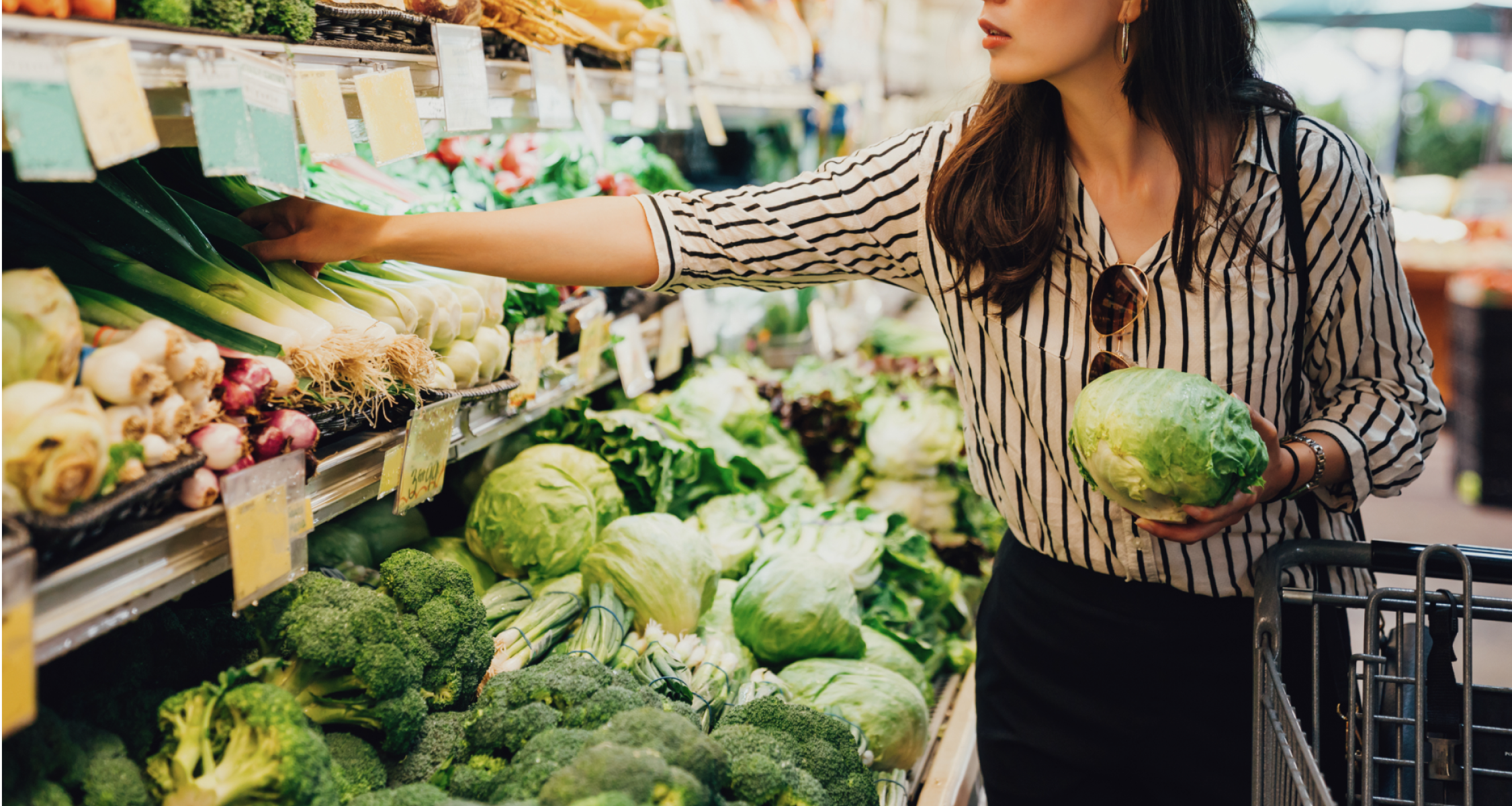 a woman choosing vegetable from a rack in a store