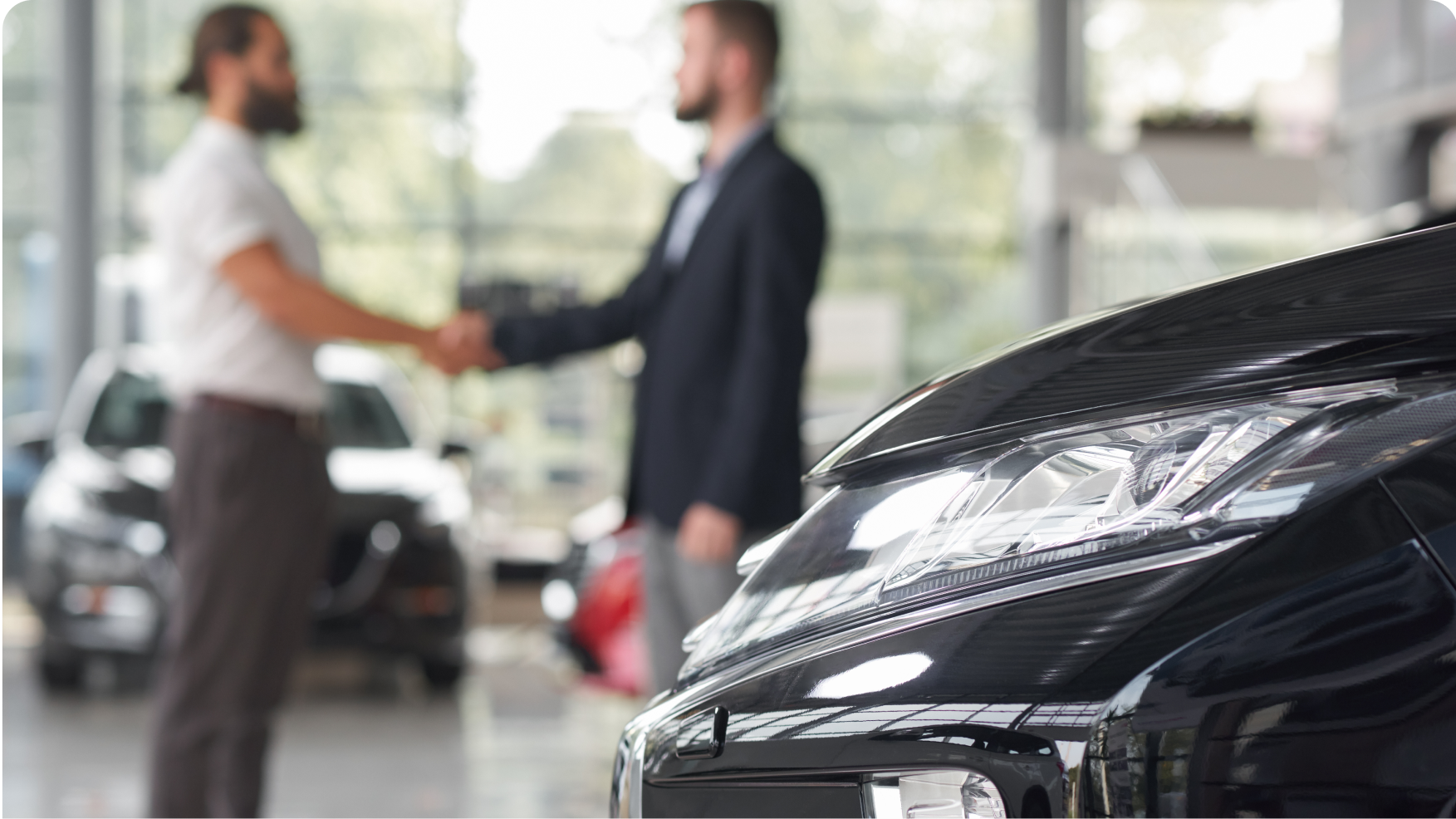 two men shaking hands in a car dealership
