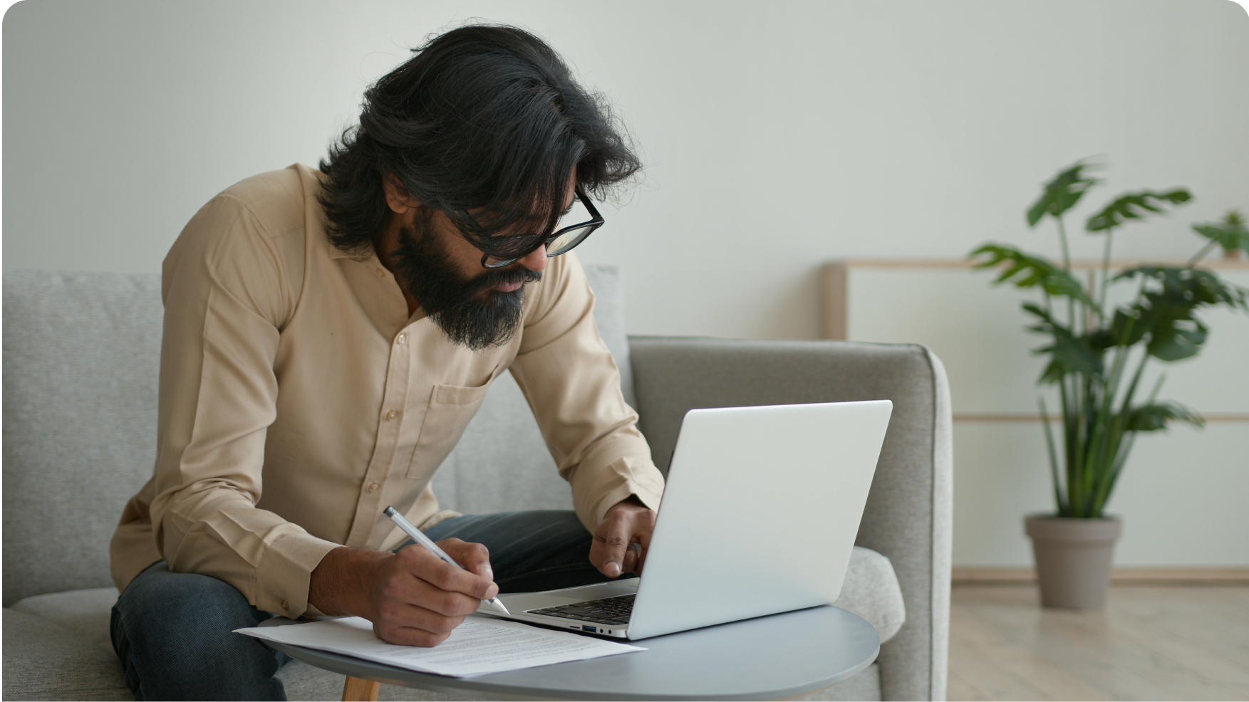 A man looking at a laptop and holding a pen