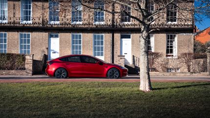 Parked side view of a red Tesla Model 3