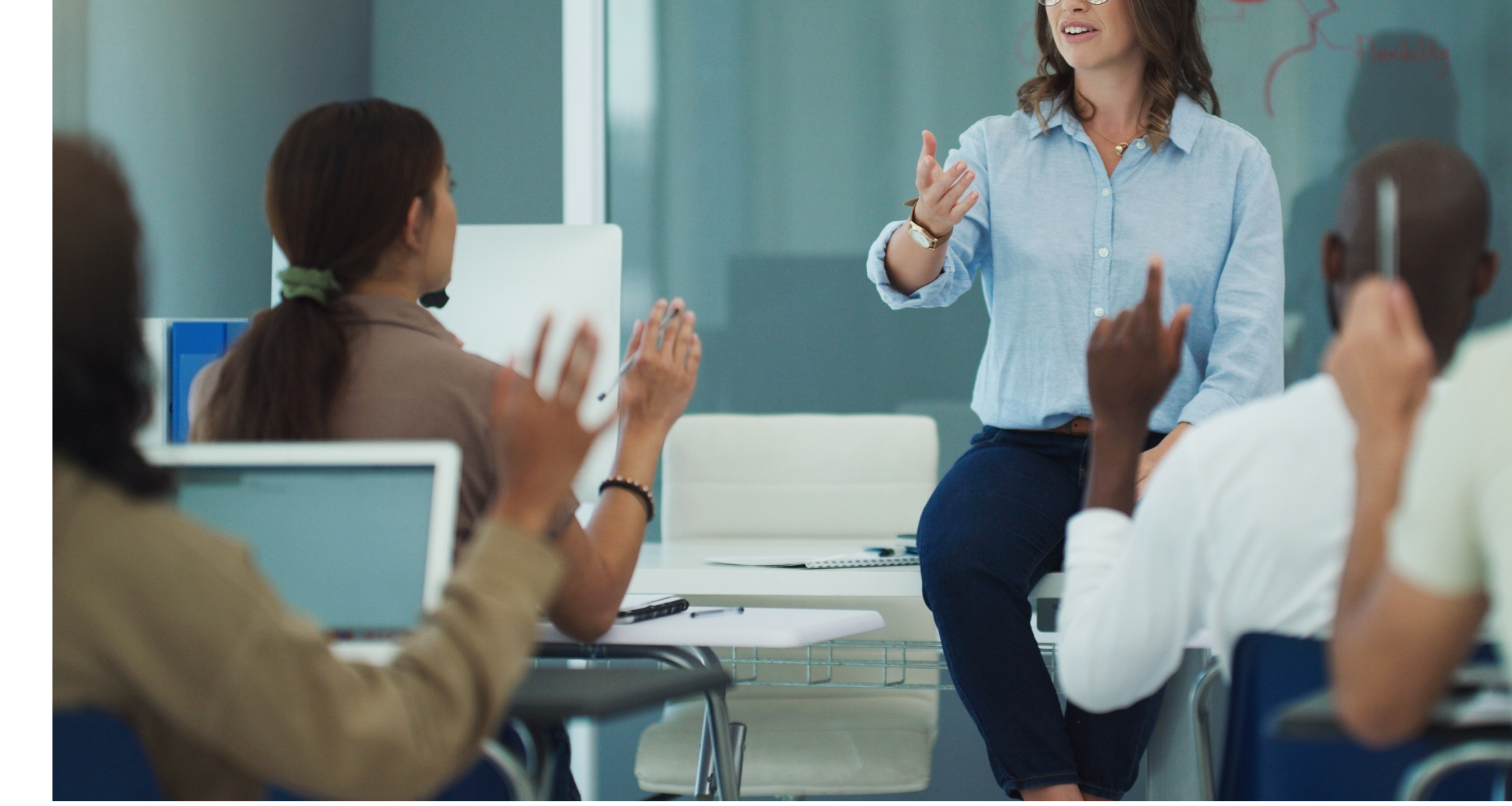 Teacher in a classroom, with students raised their hands