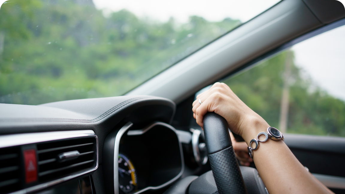 closeup image of a woman's hand on a steering wheel inside a car