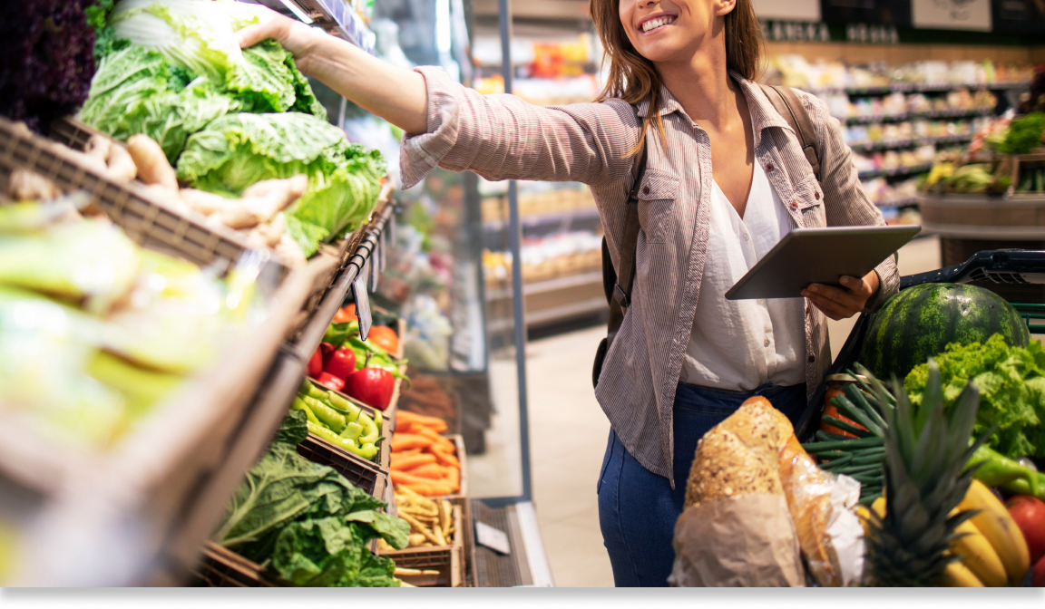A shopper reaching for vegetables while grocery shopping. 