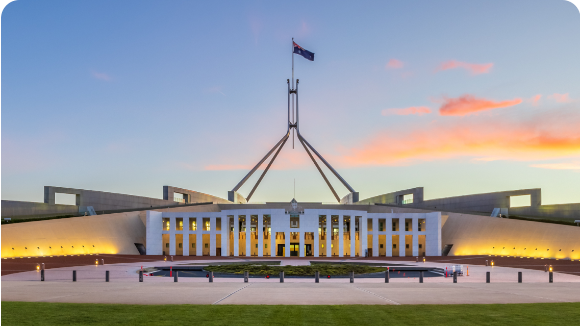 Iconic government building, Parliament House in Canberra, Australia, set against a blue sky with orange clouds.