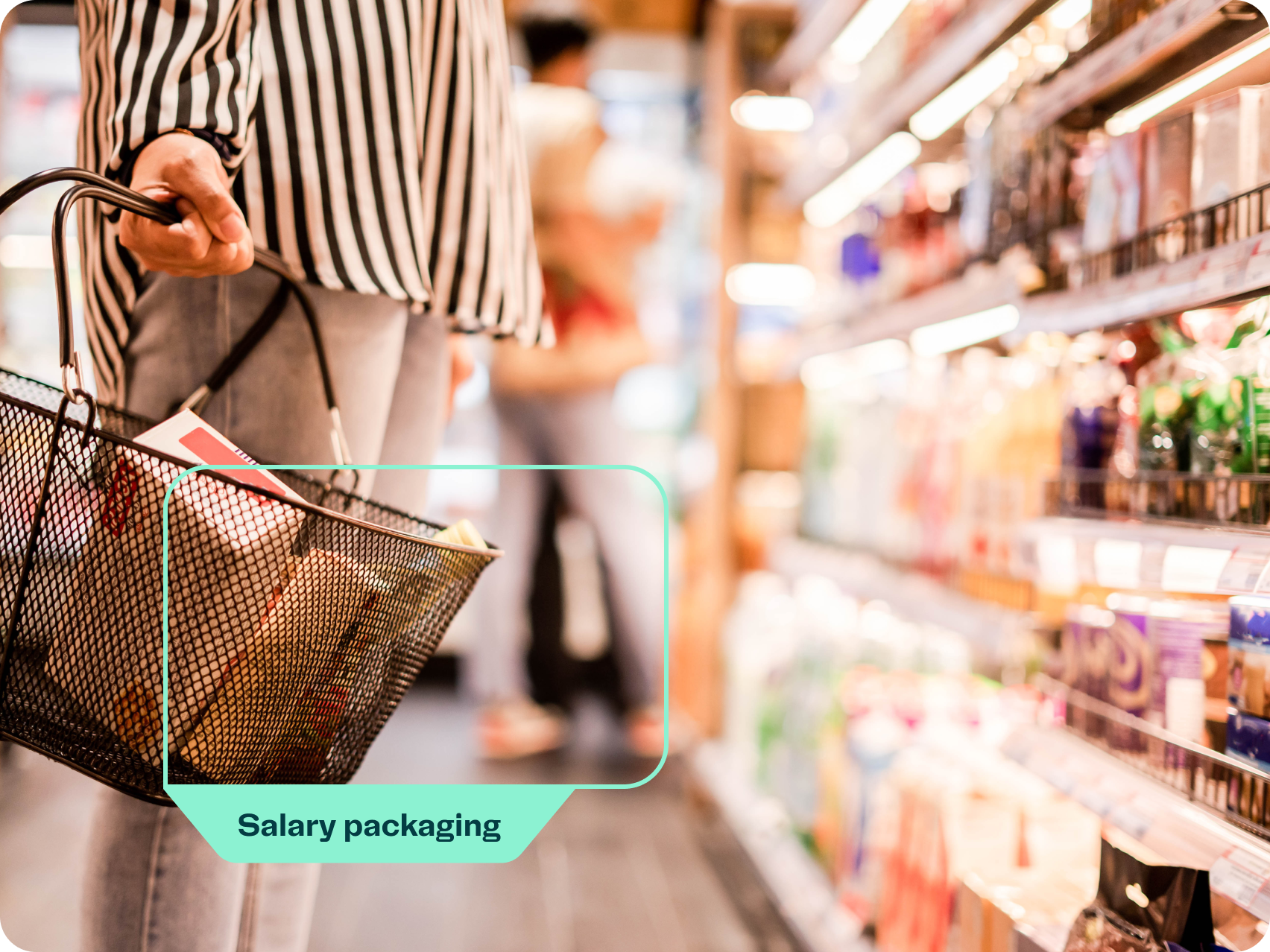 A person holding a shopping basket in a grocery store aisle with a 'Salary packaging' label highlighted on the basket to indicate being able to salary package groceries. 