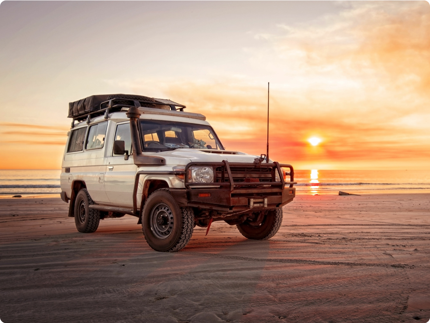 A car on a beach at sunset