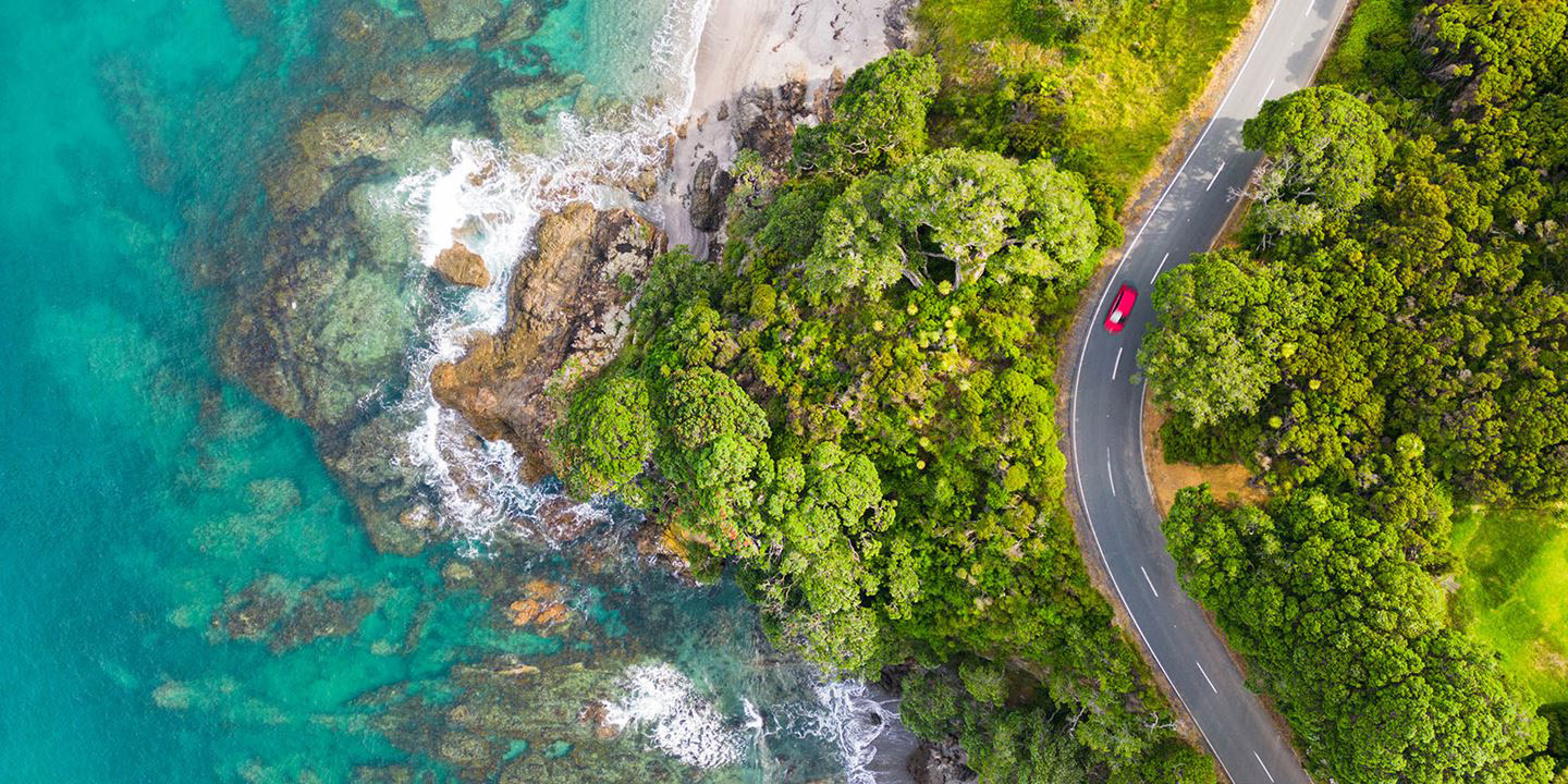 Aerial view of car driving down beachside road