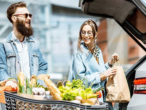Couple putting groceries in the boot of a car