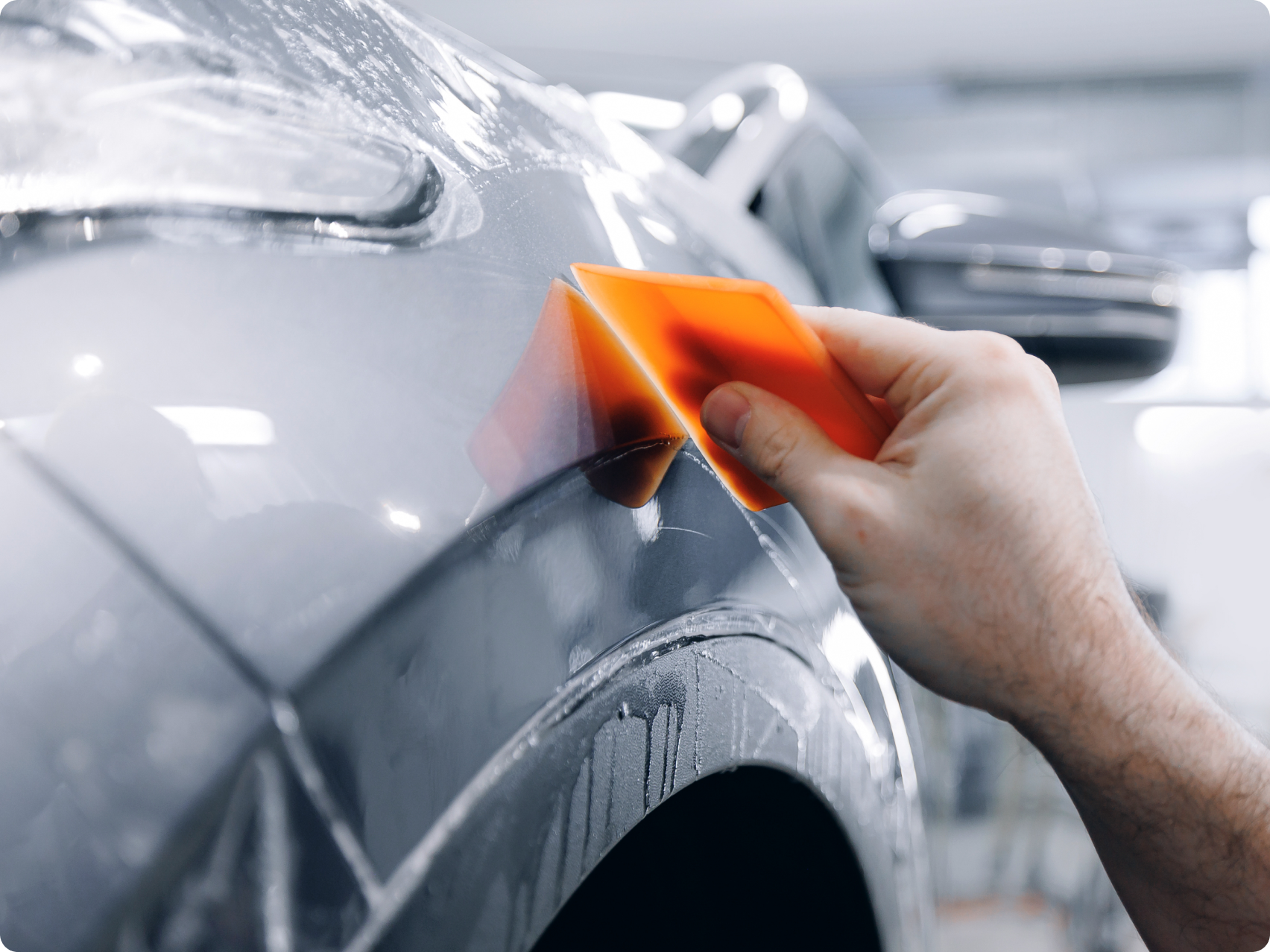 Someone repairing the paint on a silver car
